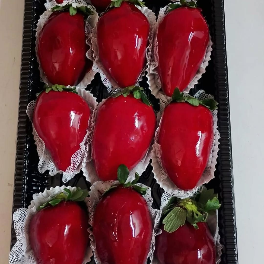 Doces de morango com cobertura vermelha brilhante, apresentados em uma bandeja